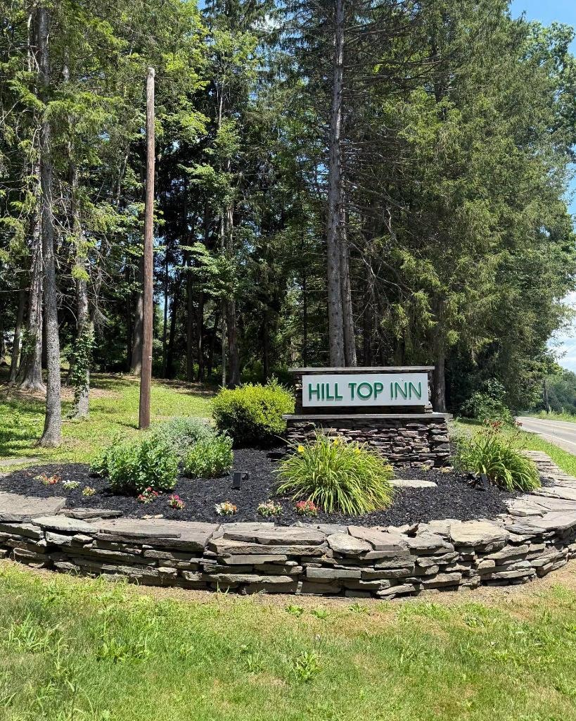 Hill Top Inn entrance sign with stone landscaping, Elmira NY